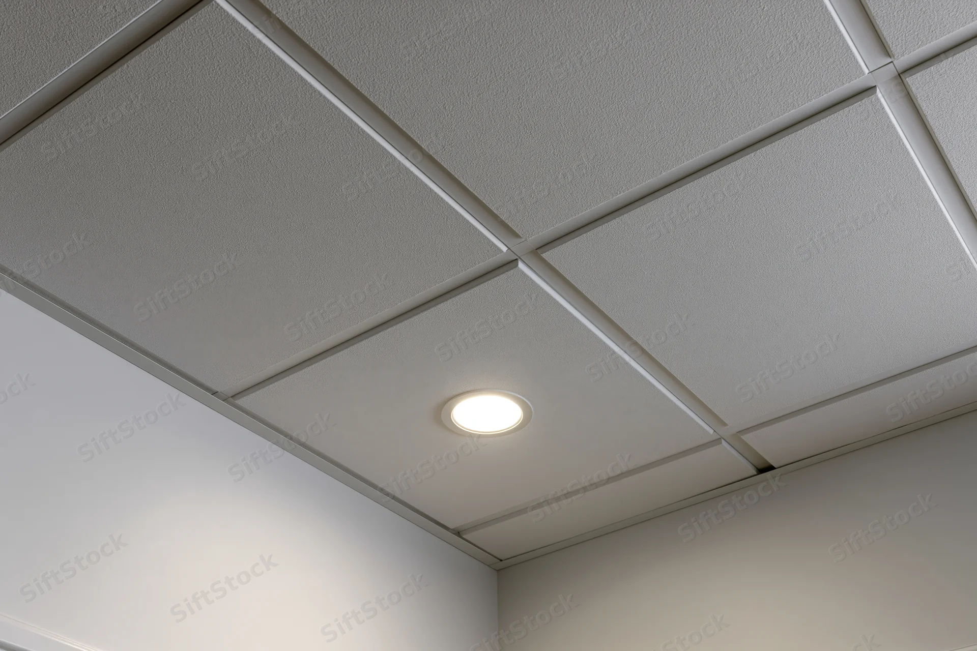 Corner junction of a modern office drop ceiling with recessed light fixture