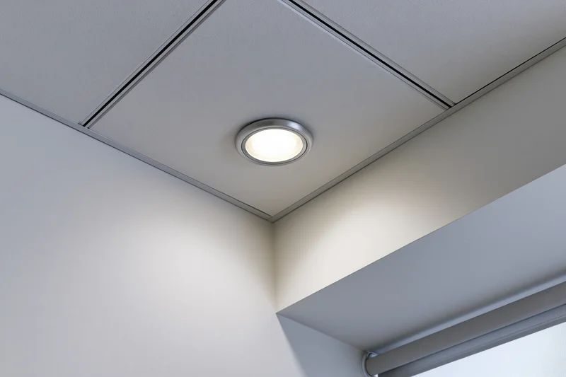 Recessed circular light fixture in a modern office ceiling corner