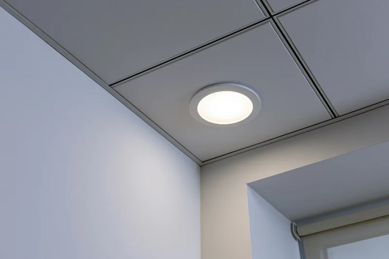 Recessed circular light fixture in a modern office ceiling corner