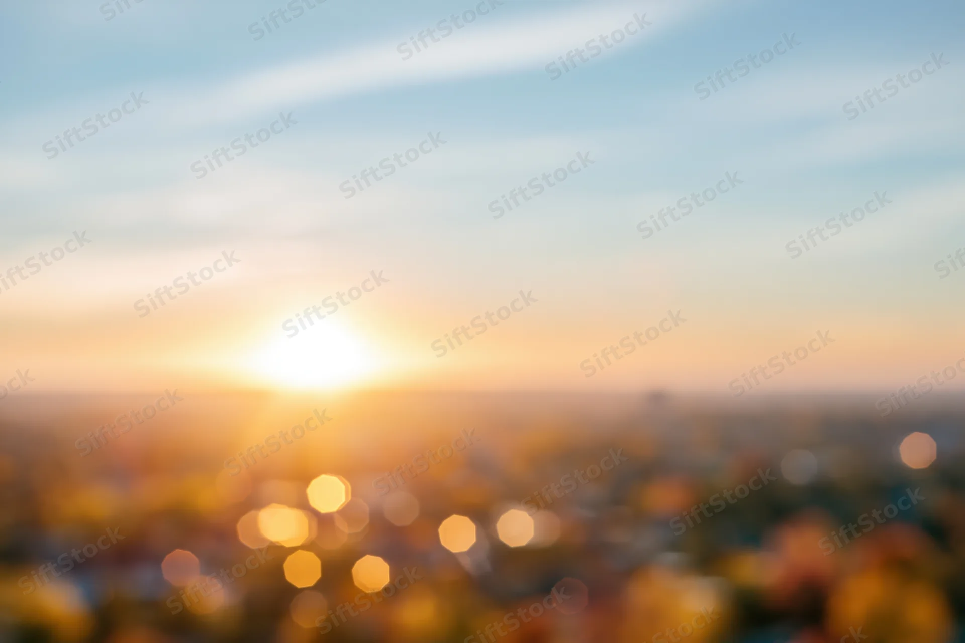 Defocused cityscape at sunset with bokeh lights and warm sky glow