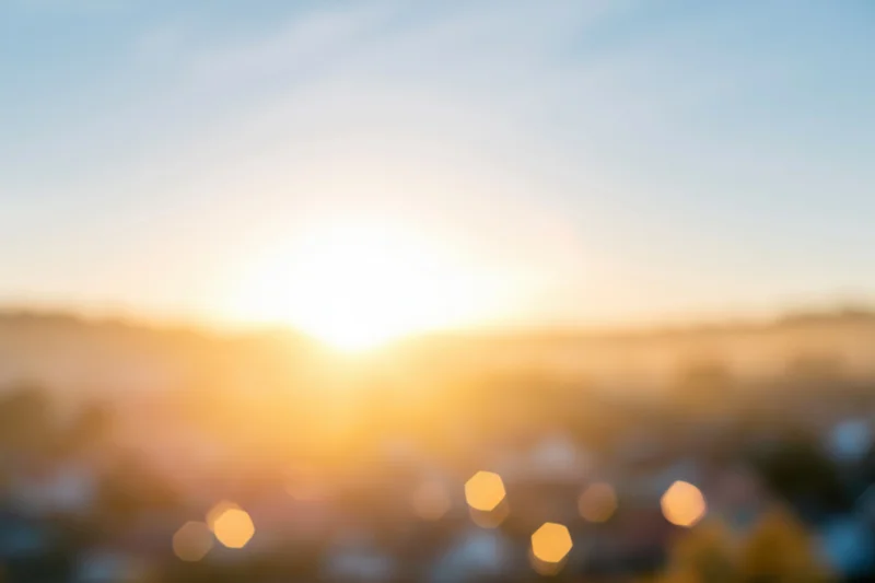Defocused sunrise over urban landscape with bokeh lights and soft golden glow