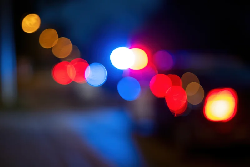 Defocused police emergency lights flashing at night on a city street