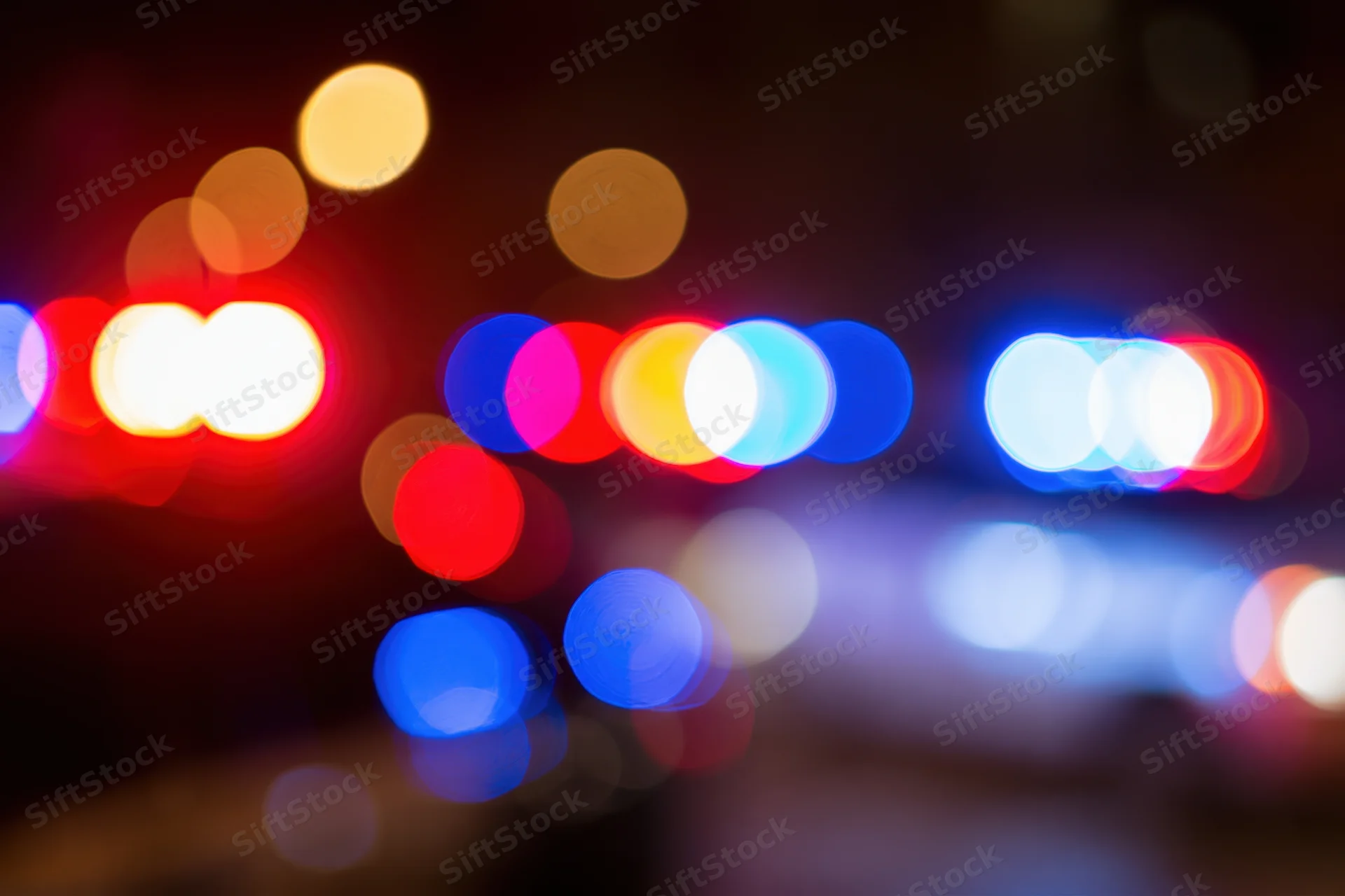 Defocused police emergency lights flashing at night in an urban setting