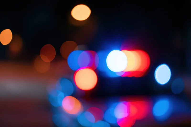 Defocused police emergency lights flashing at night on wet pavement
