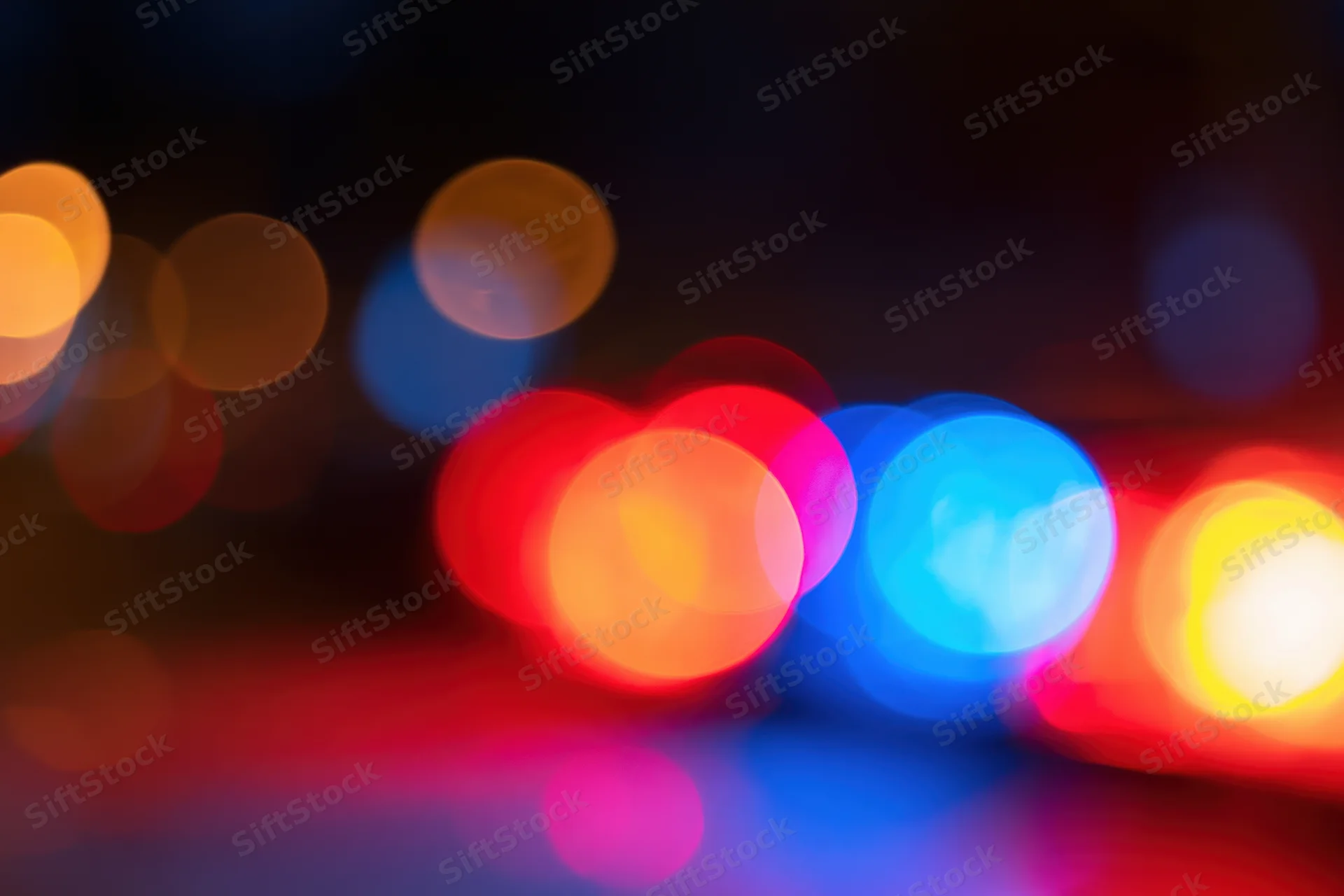 Defocused police emergency lights flashing at night in an urban setting
