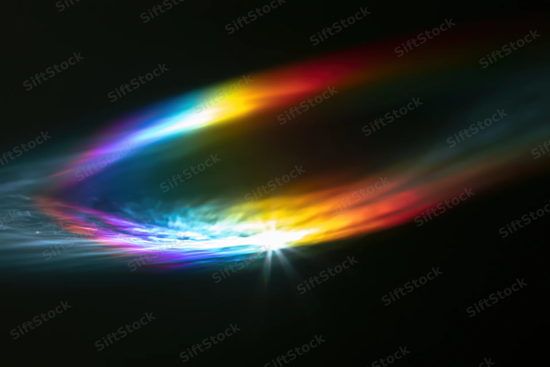 Rainbow light diffraction pattern floating against dark background with bright central glow and colorful arcs