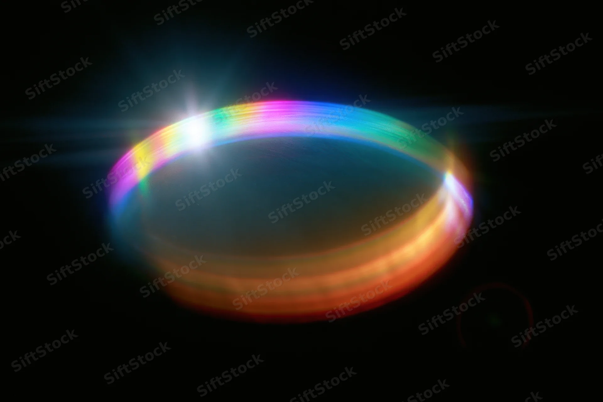 Defocused rainbow light refraction oval bloom floating against dark background with lens flare and chromatic dispersion