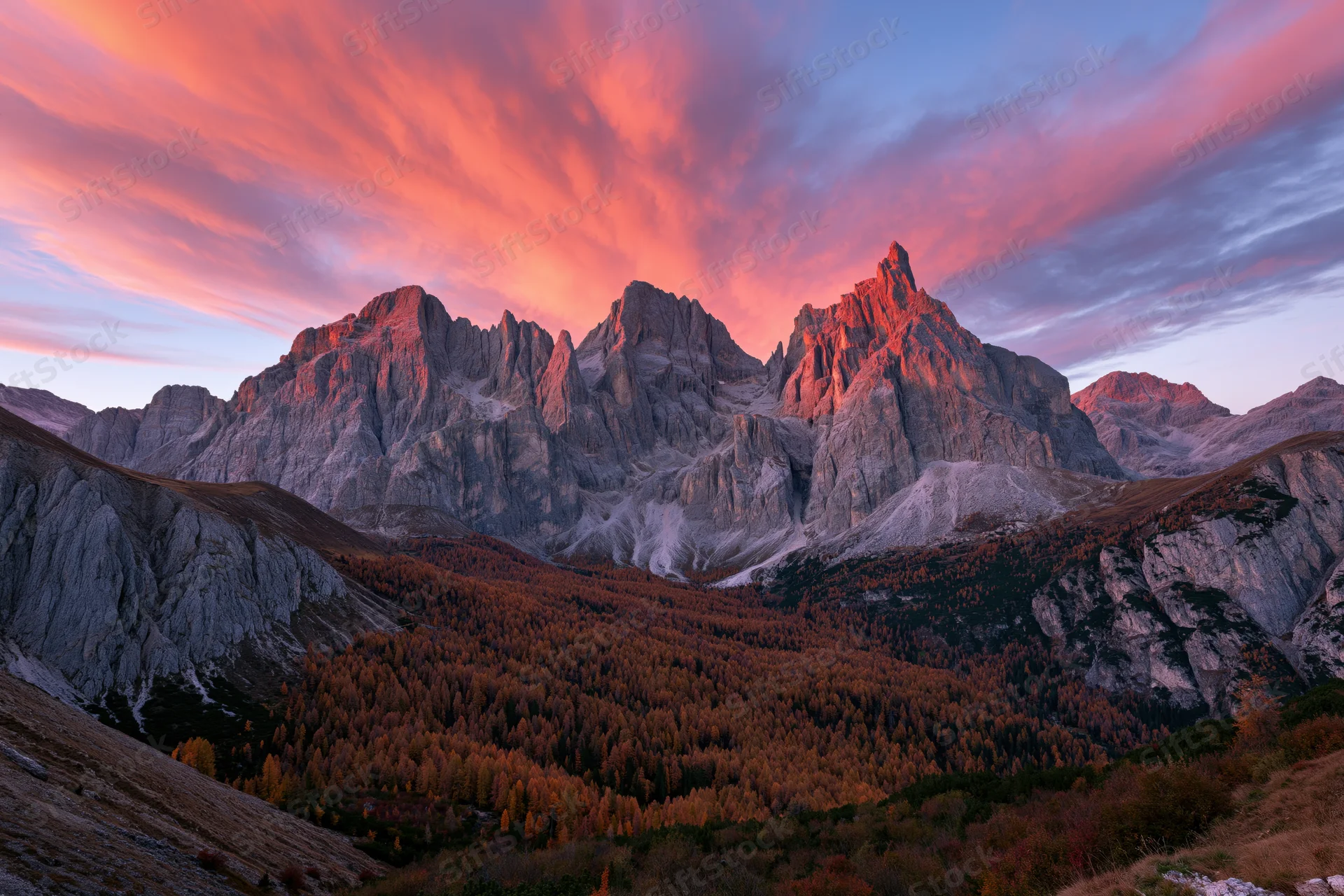 Jagged limestone dolomite peaks at sunset above autumn forested valley