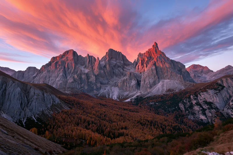 Jagged limestone dolomite peaks at sunset above autumn forested valley