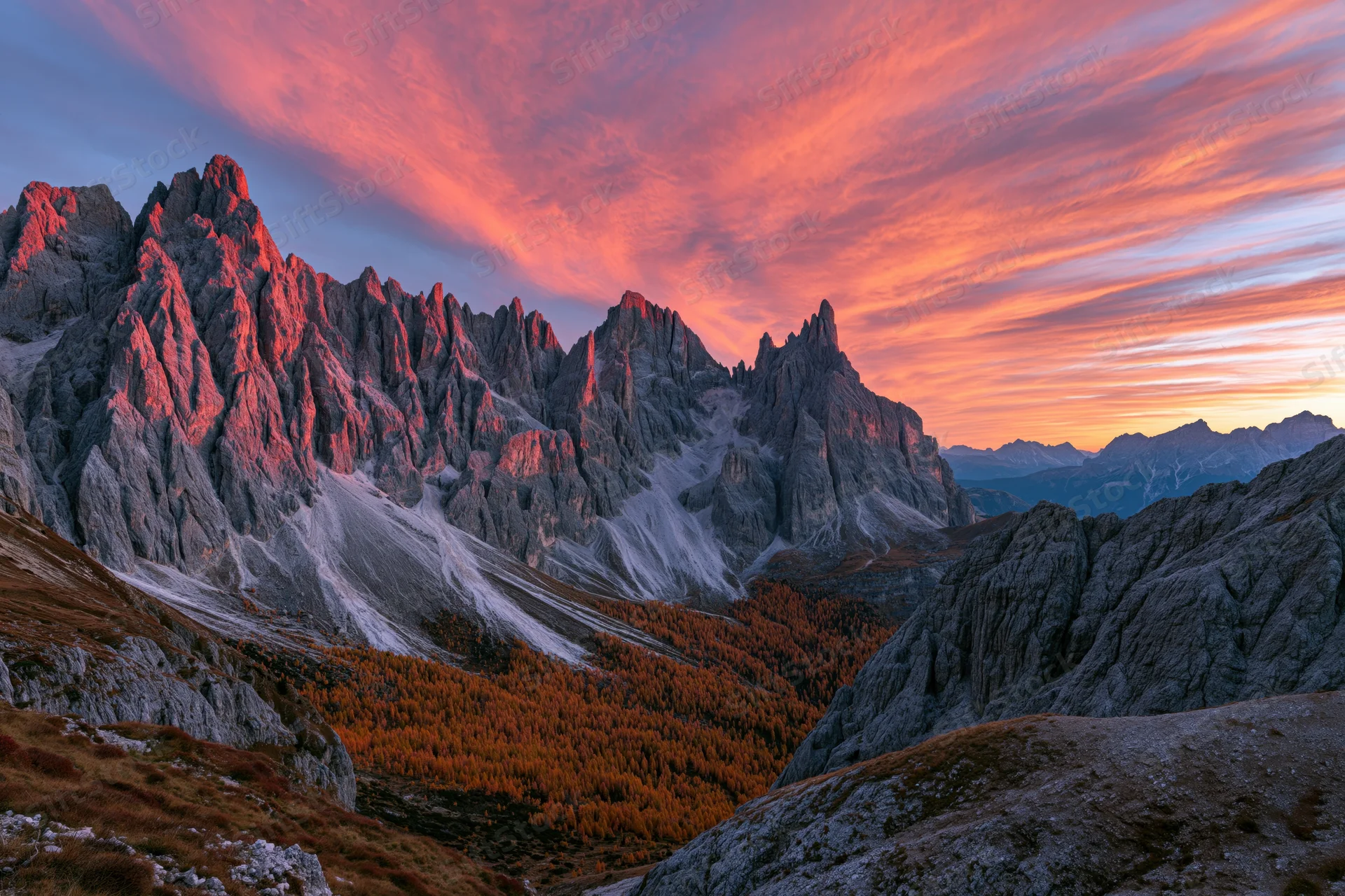 Jagged limestone dolomite peaks at sunset with autumn larch forest in valley below