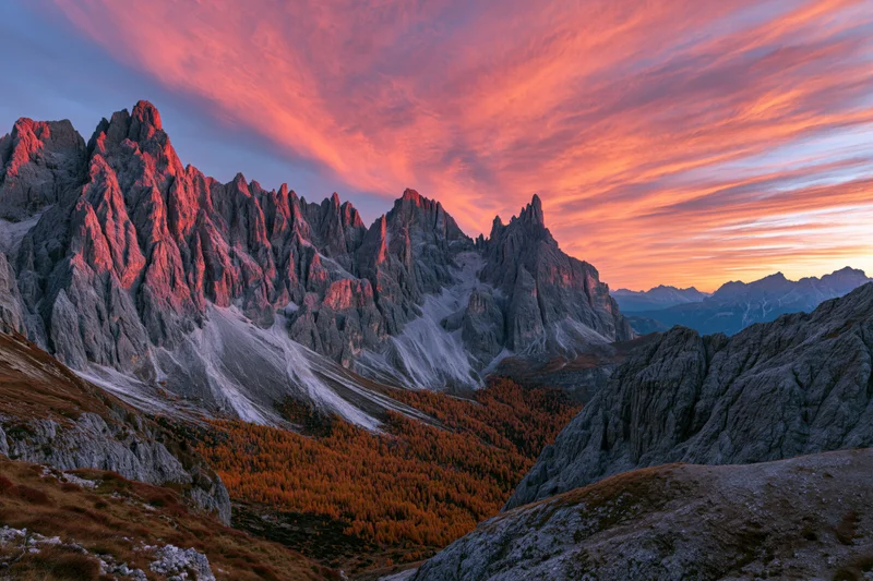 Jagged limestone dolomite peaks at sunset with autumn larch forest in valley below