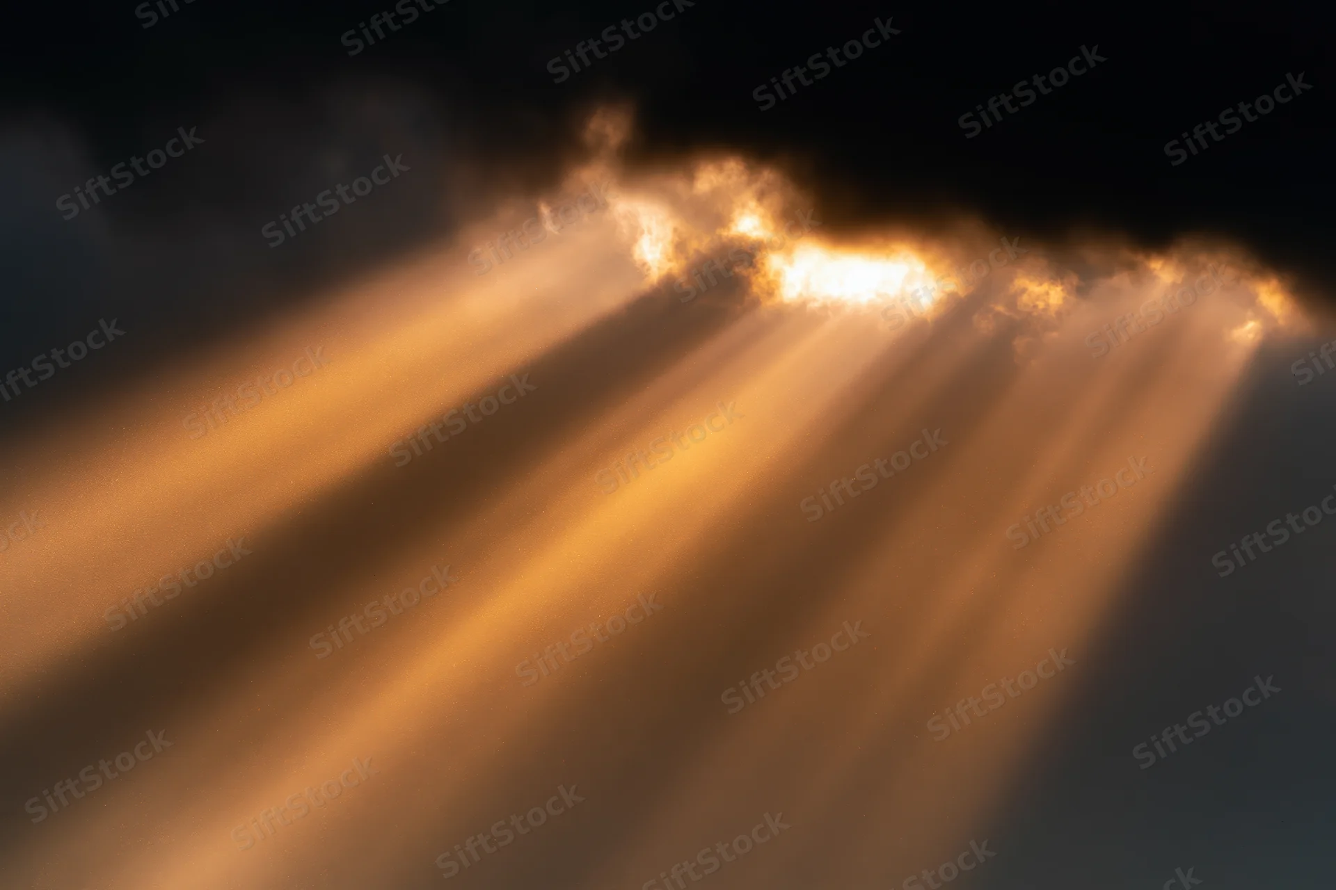 Golden sunbeams breaking through dark storm clouds in the sky