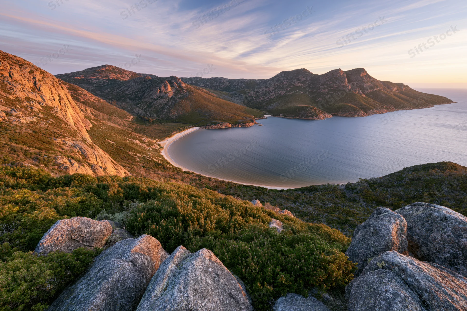 Rocky hilltop overlooking a coastal bay at sunset
