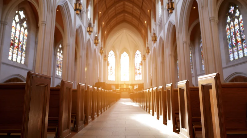 Empty church nave viewed down central aisle with sunlight streaming through stained glass windows