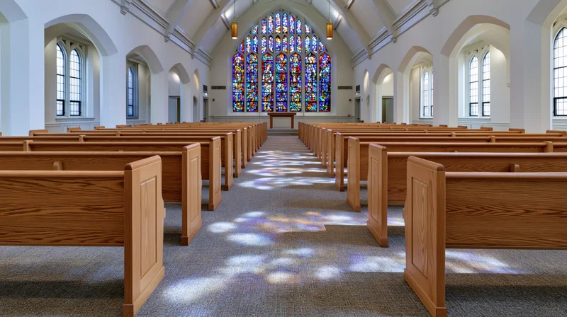 Empty church interior with wooden pews arranged in rows leading to altar under stained glass window