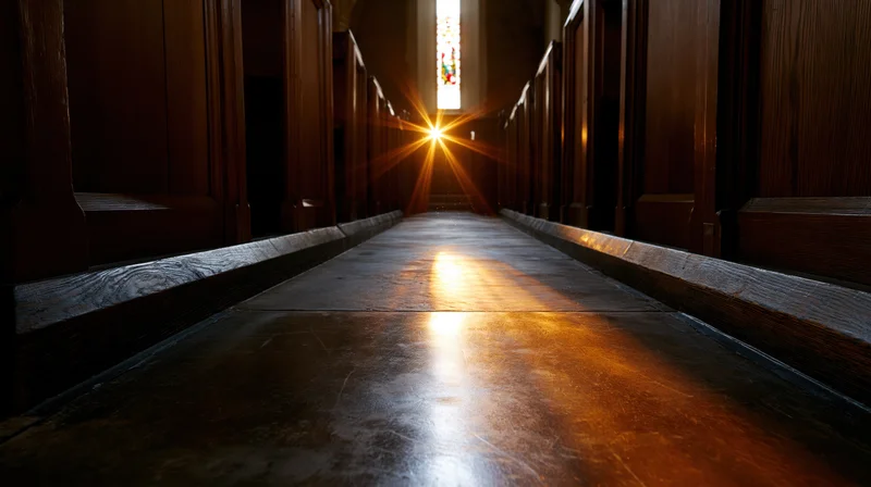 Empty church aisle with wooden pews and sunlight streaming through stained glass window