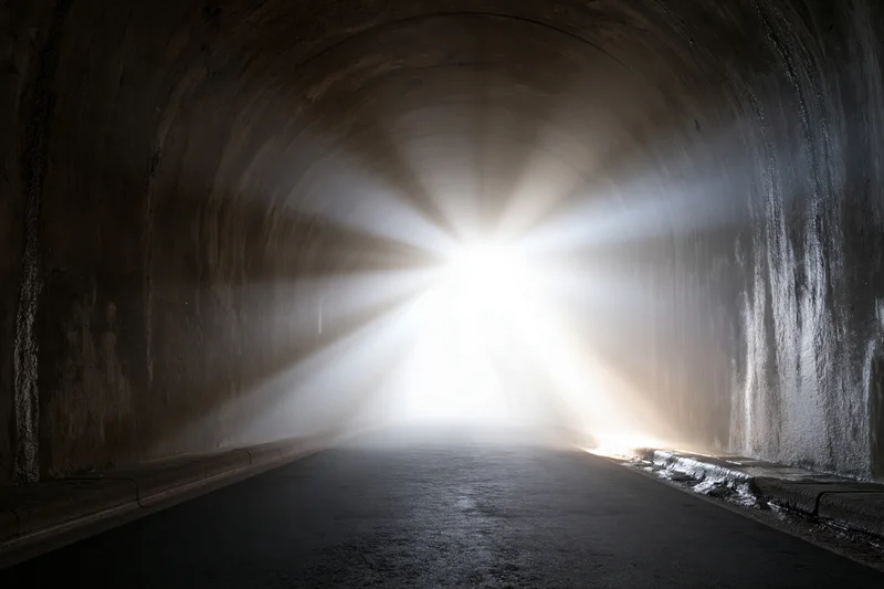 Concrete road tunnel interior viewed toward bright light at exit