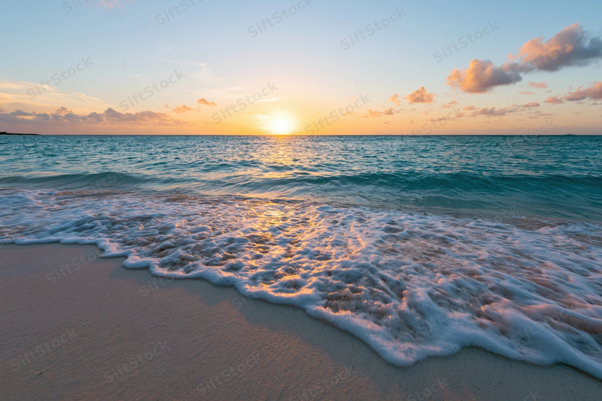 Gentle shallow wave washing onto sandy beach at sunset