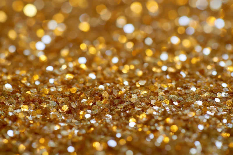 Gold glitter texture in extreme closeup with sparkling bokeh effect