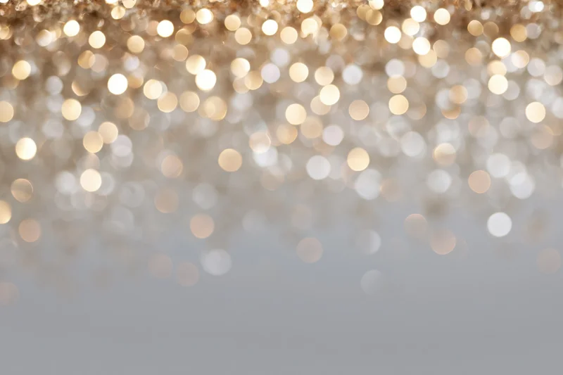 Out-of-focus golden and white bokeh lights forming a festive abstract background with copyspace at bottom