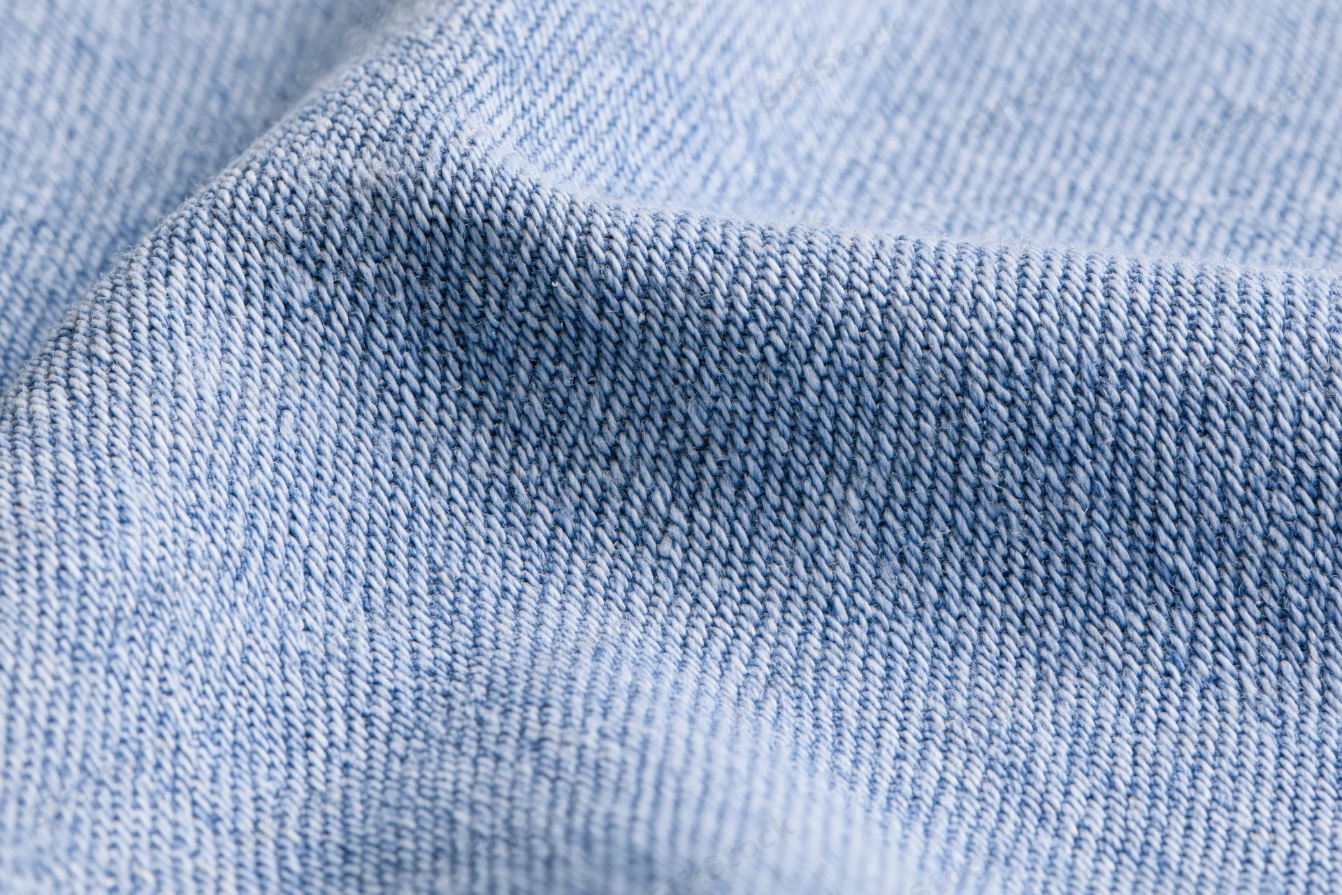 Light washed denim fabric in extreme close-up showing detailed twill weave texture