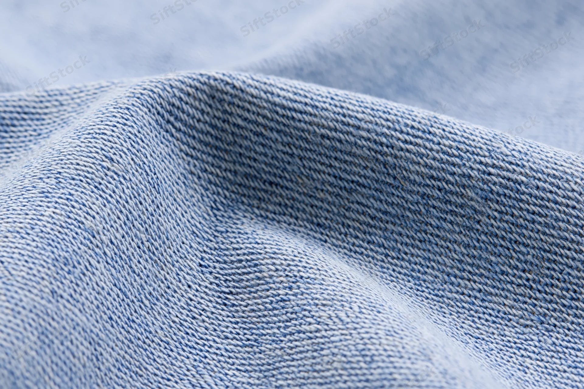 Light washed denim fabric in extreme closeup showing detailed weave texture