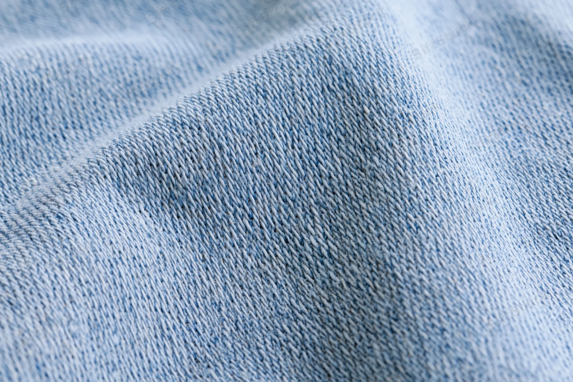 Light washed denim fabric in extreme closeup showing detailed weave texture