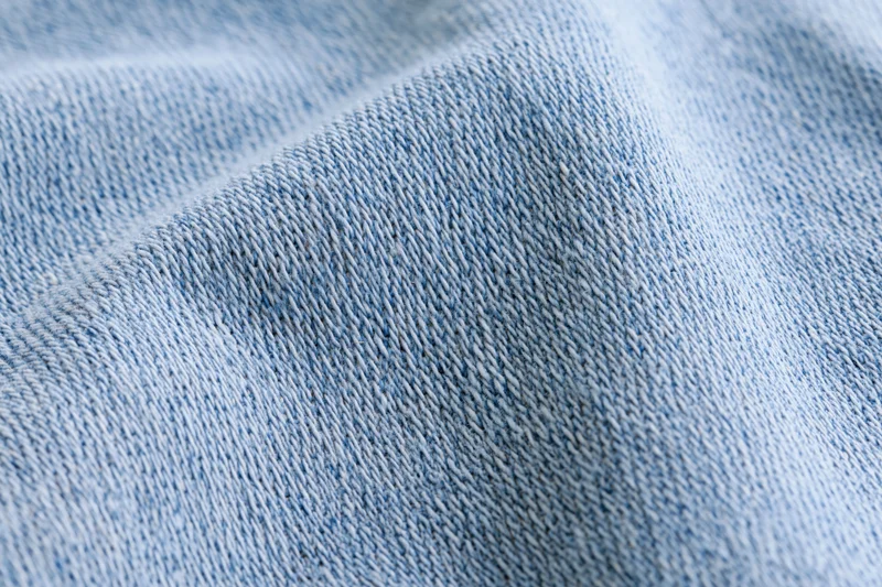 Light washed denim fabric in extreme closeup showing detailed weave texture