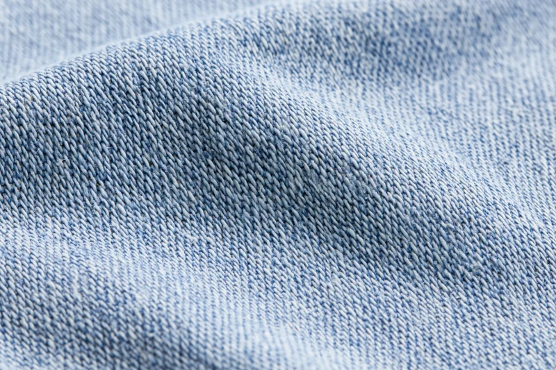 Light washed denim fabric in extreme closeup showing detailed weave and texture