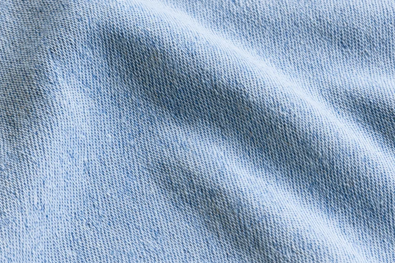 Light washed denim fabric in extreme closeup showing detailed weave and texture