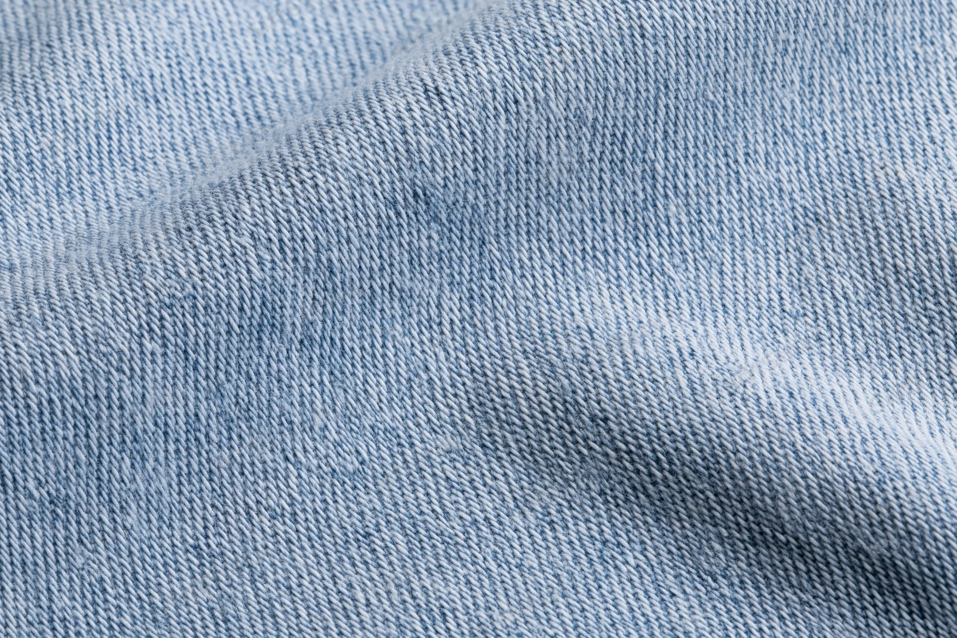 Light washed denim fabric in extreme closeup showing detailed weave and texture
