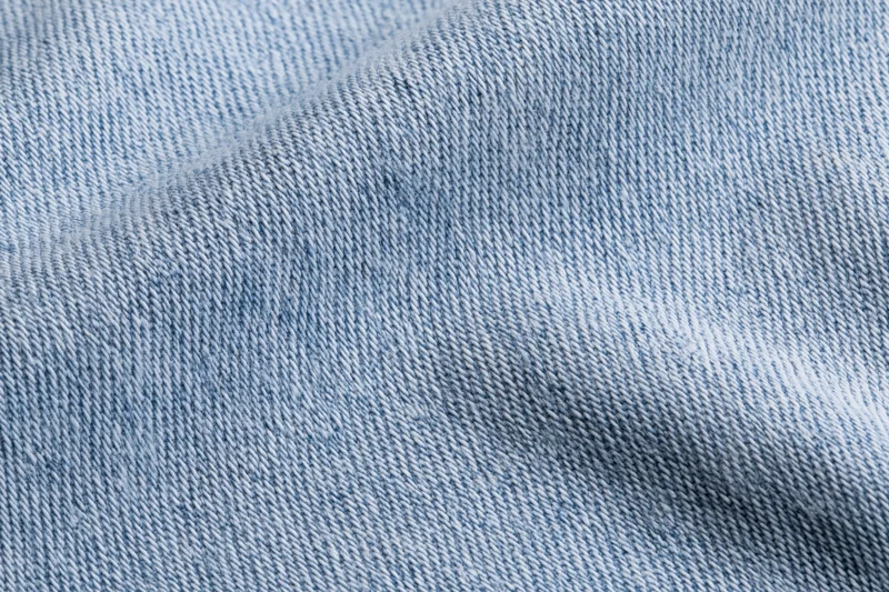 Light washed denim fabric in extreme closeup showing detailed weave and texture