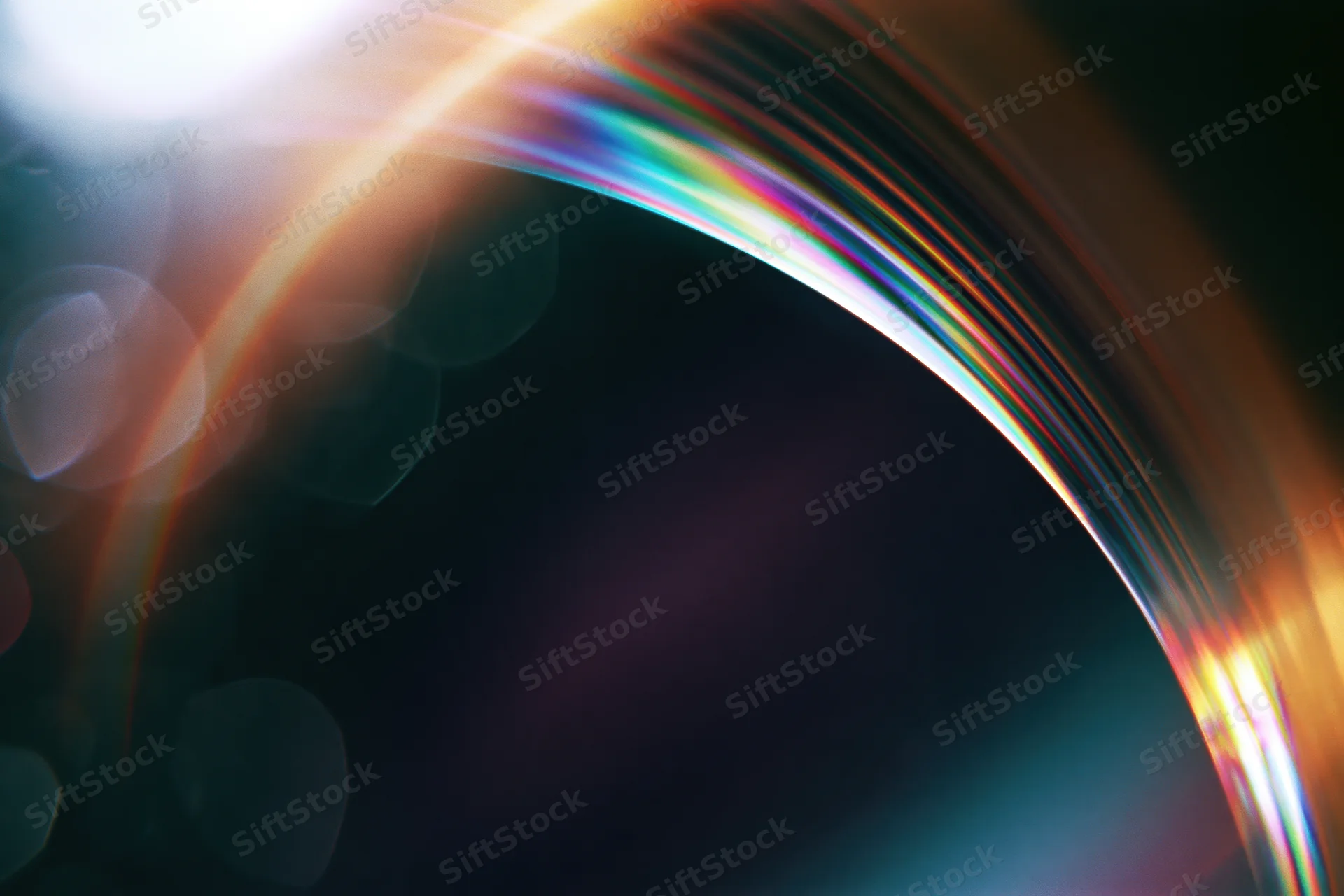 Curved glass lens reflecting rainbow light spectrum with bokeh highlights in dark background
