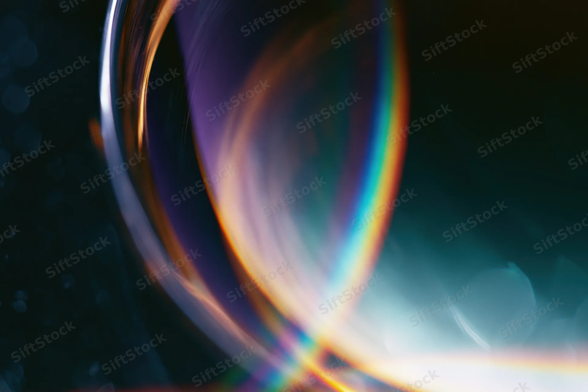 Close-up of a glass sphere reflecting rainbow light against a dark background