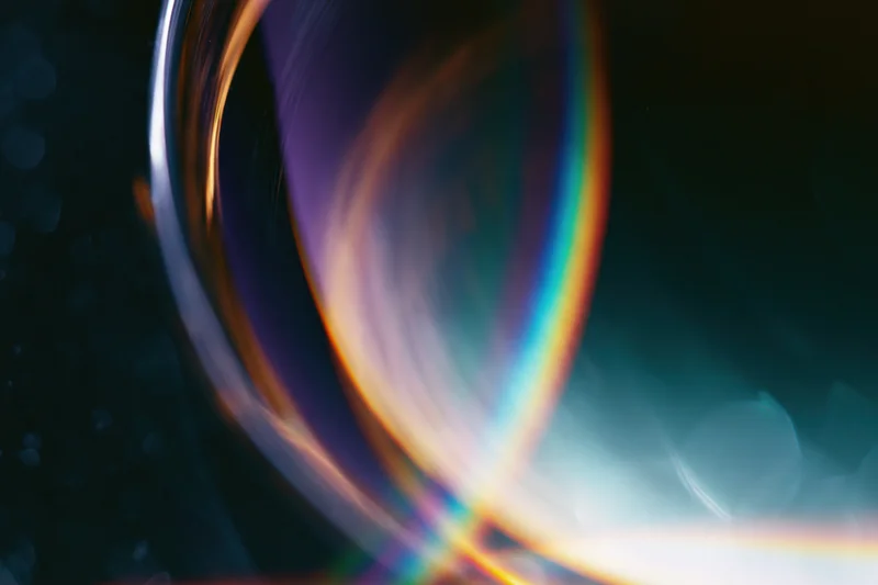 Close-up of a glass sphere reflecting rainbow light against a dark background