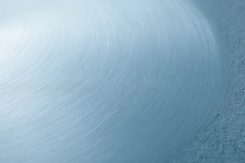 Brushed light blue metal surface filling the frame with circular texture and shallow depth of field