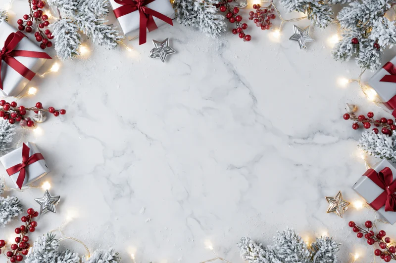 Christmas border frame with gifts, lights, and pine branches on white marble surface