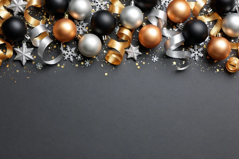 Christmas ornaments arranged along the top edge of a dark surface with copyspace below