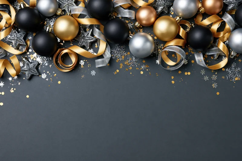 Christmas ornaments arranged along the top edge of a dark surface with copyspace below