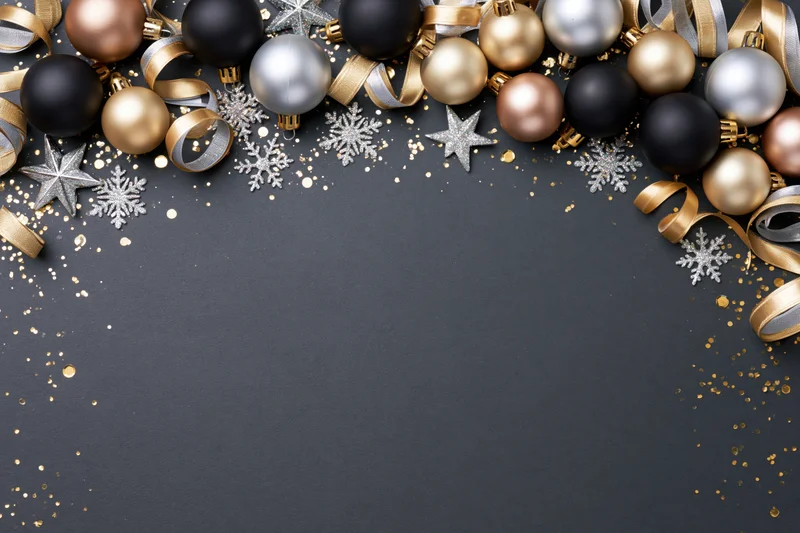 Christmas ornaments arranged along the top edge of a dark surface with copyspace below