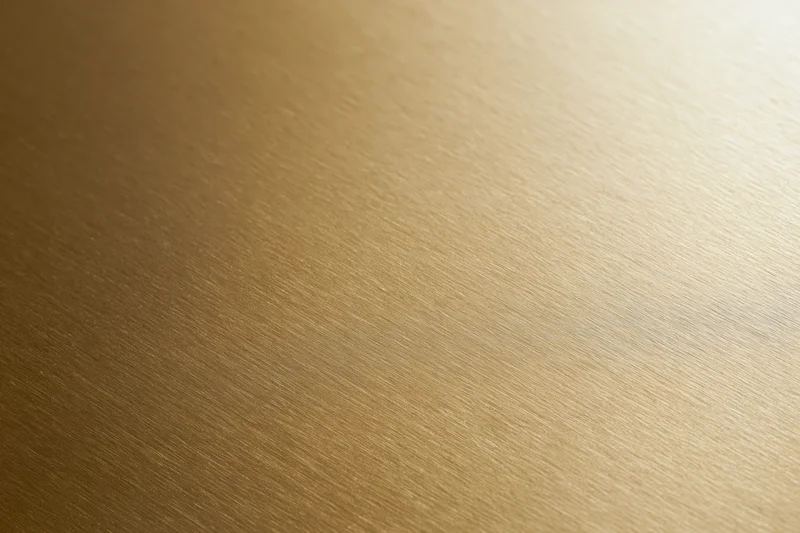 Flat matte gold metallic surface filling the frame with subtle brushed texture and warm light gradient