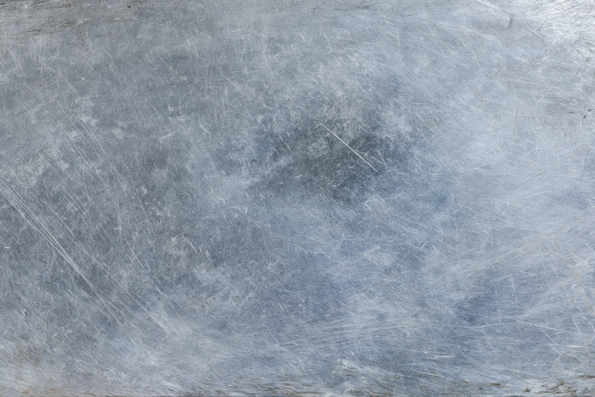 Worn metal surface covered in fine scratches and scuffs showing signs of use and abrasion