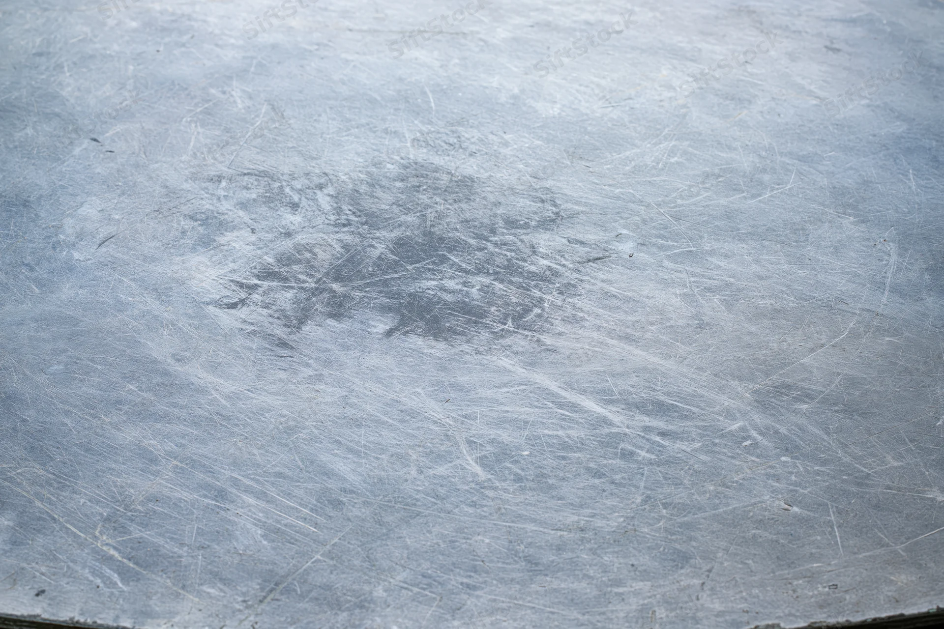 Flat worn metal surface covered in fine scratches and scuffs
