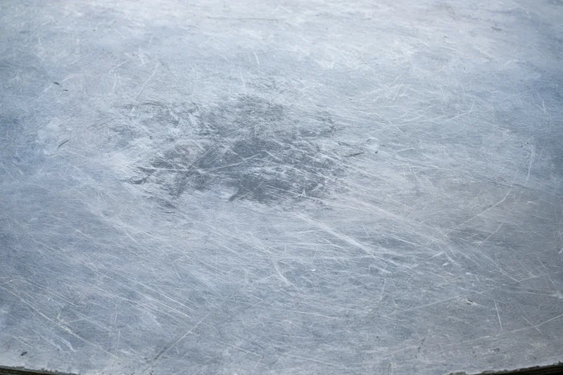 Flat worn metal surface covered in fine scratches and scuffs