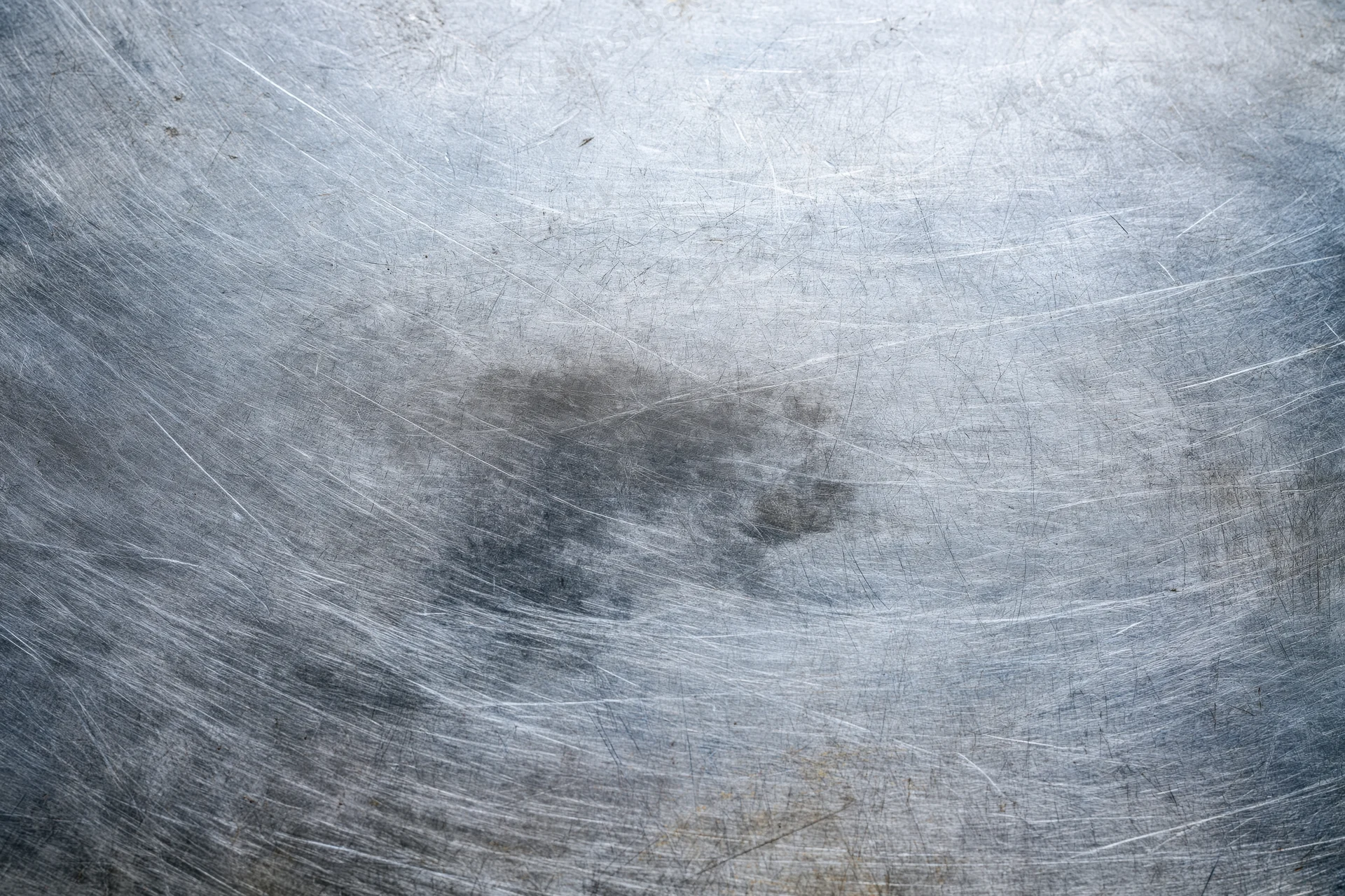 Worn metal surface with fine scratches and scuff marks showing signs of use and aging