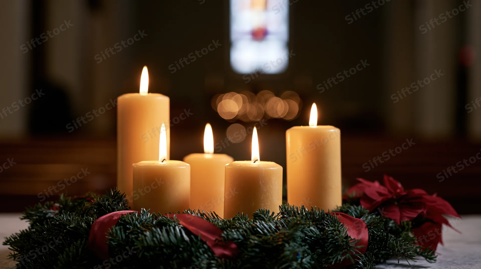Advent candles burning on an evergreen wreath in a church interior