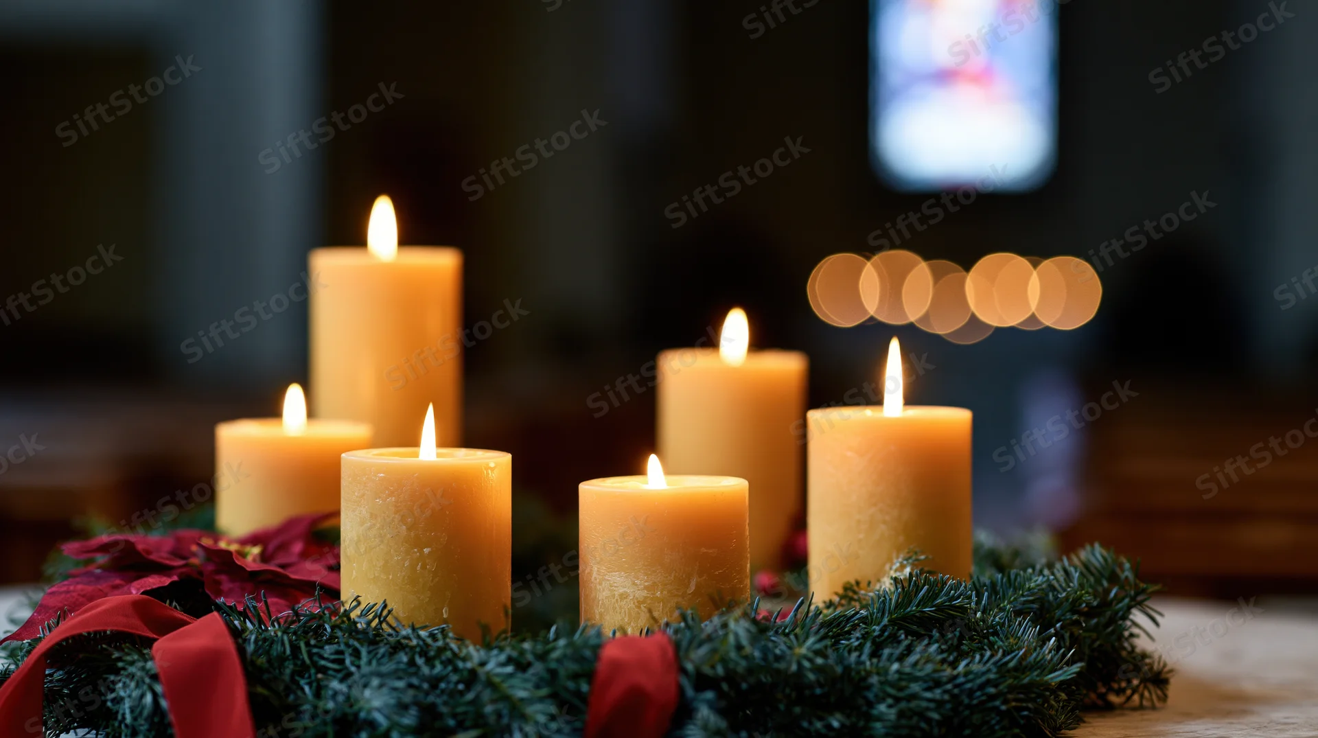 Advent candles burning on an evergreen wreath in a church interior