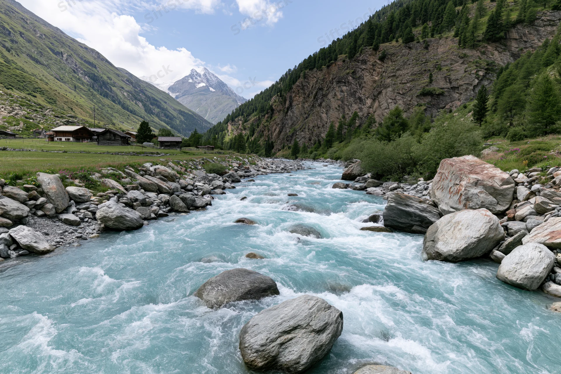 Glacial turquoise river rushing over rounded boulders through alpine valley with snow-capped peak and forested slopes