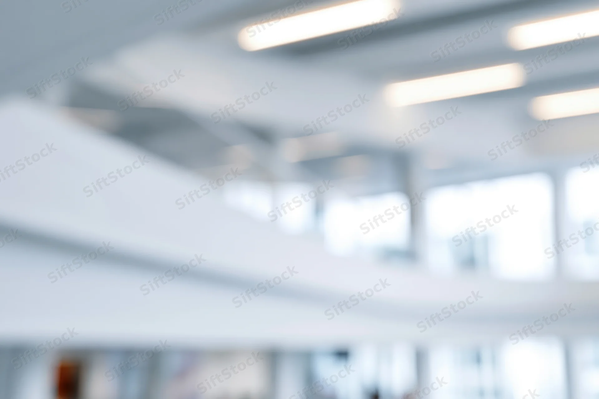 Defocused interior of a bright modern office with ceiling lights and windows