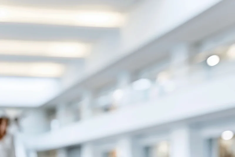 Blurred interior of a bright modern office with ceiling lights and architectural features
